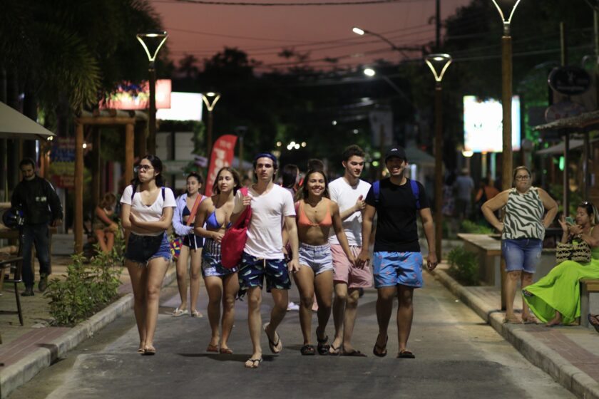 jovens caminham em rua na Praia do Francês, AL